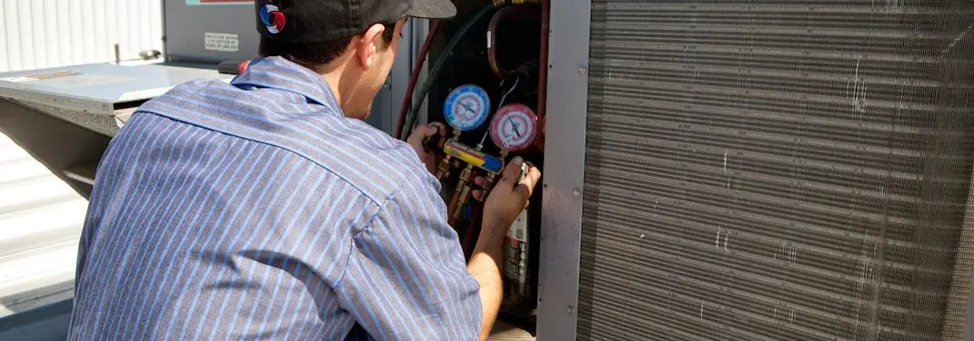 HVAC technician servicing a condenser unit in Artondale