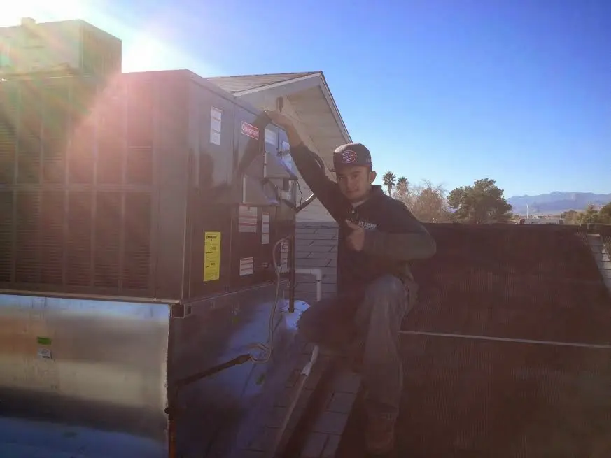 HVAC technician performing AC Tune-Up on a rooftop unit in Artondale